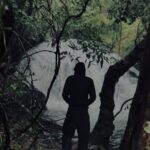 best travel photographer in wayand a man standing in ah forest river